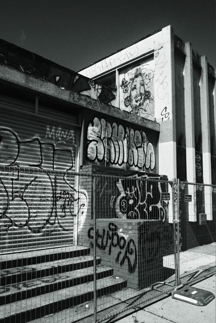 Black and white photograph of a graffiti covered storefront building